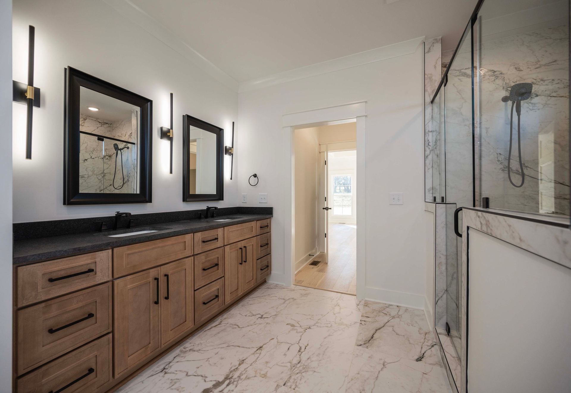 Modern bathroom with double vanity, marble floor, and glass shower.