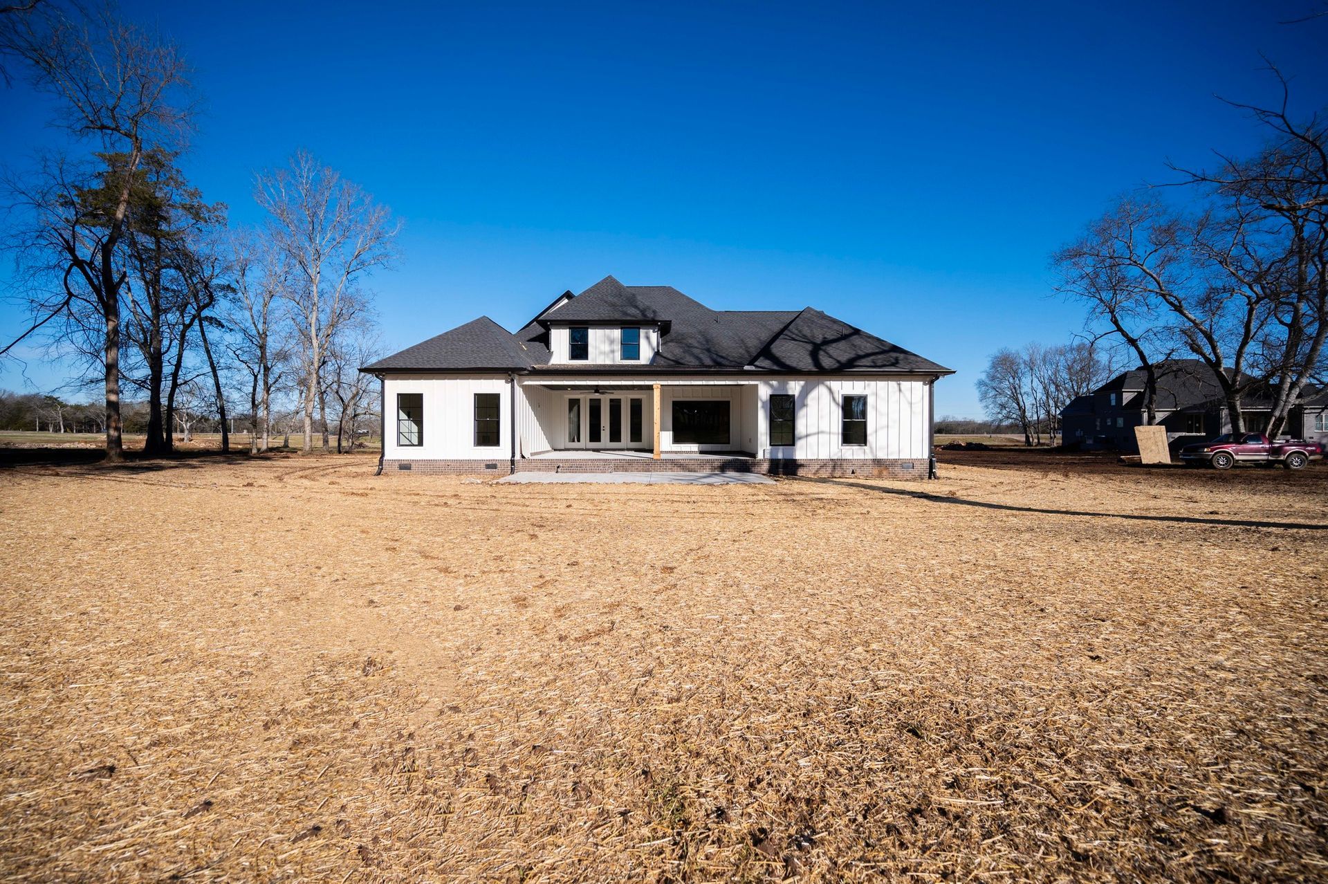 White house with black roof in a field under a bright blue sky.