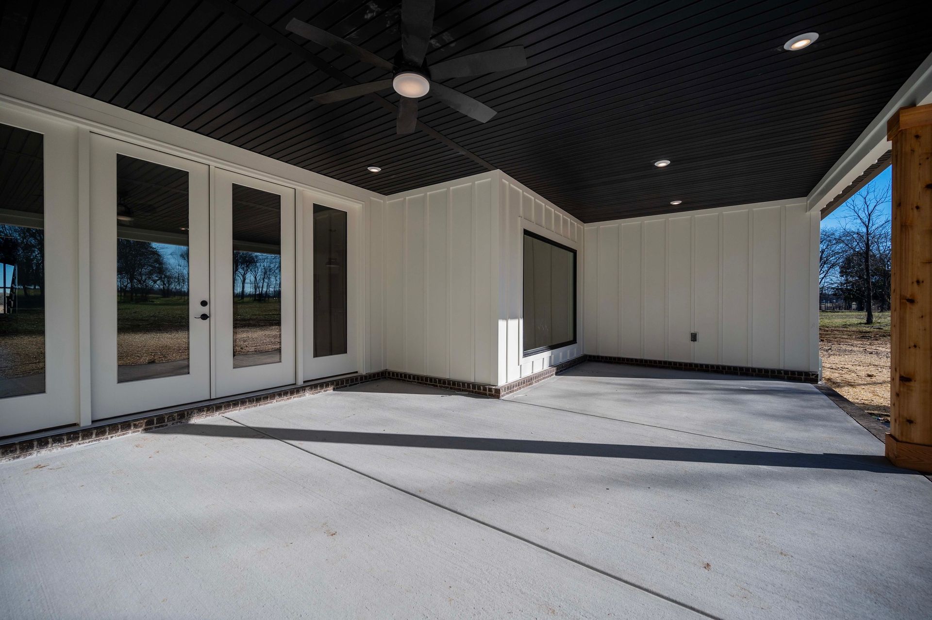 Covered patio with a black ceiling, white walls, and French doors.