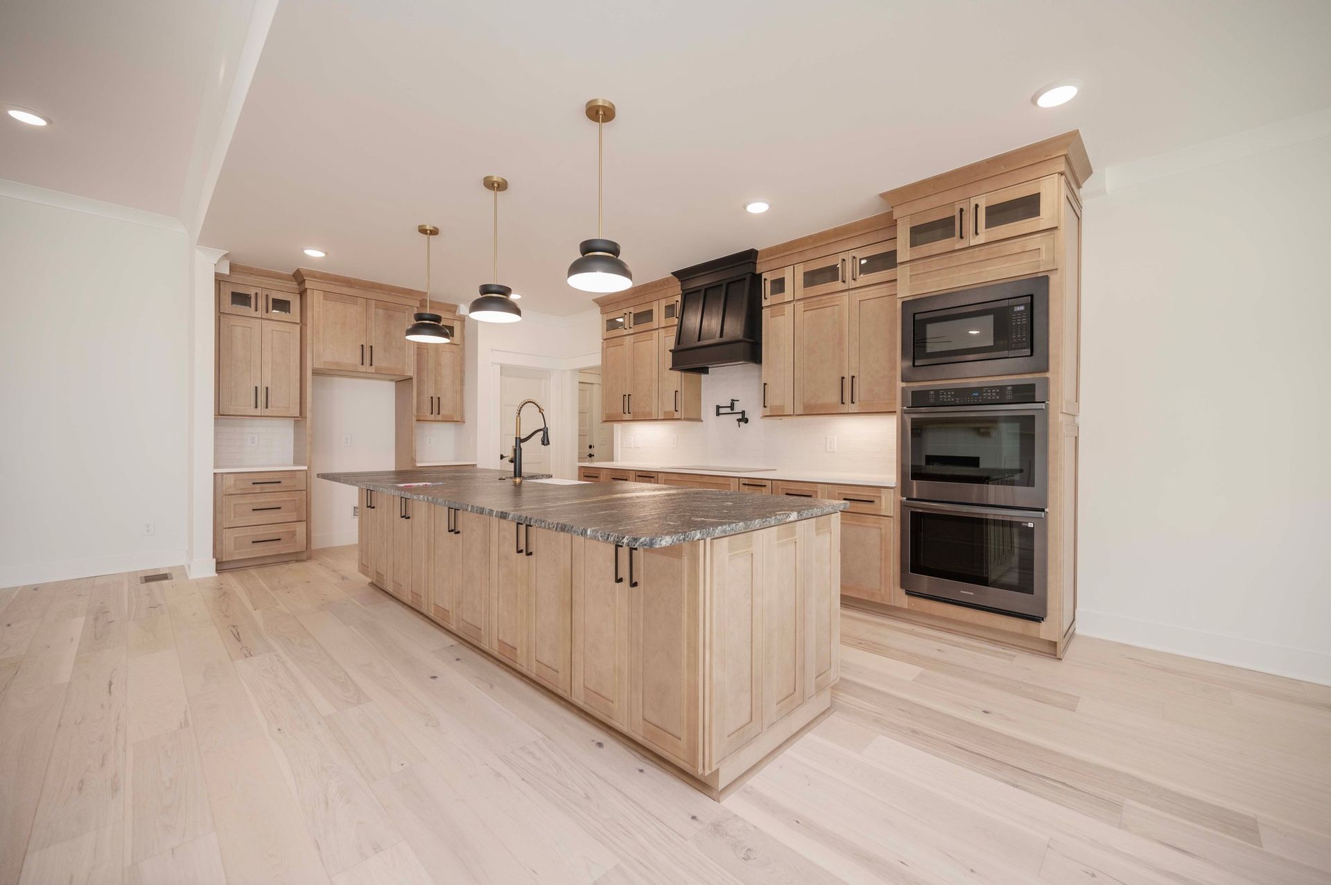 Modern kitchen with wood cabinets, large island, stainless appliances, and pendant lights.