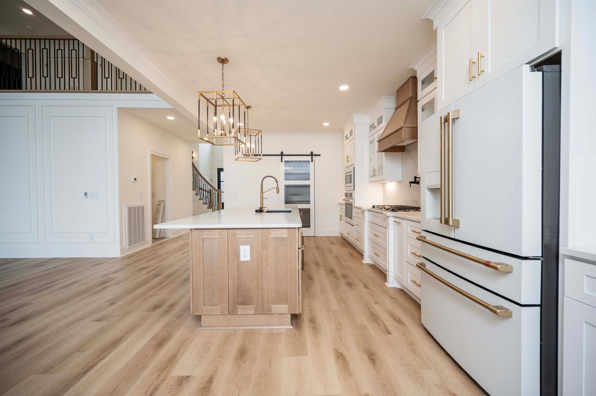 Modern kitchen with wood floors, white cabinets, and a central island.