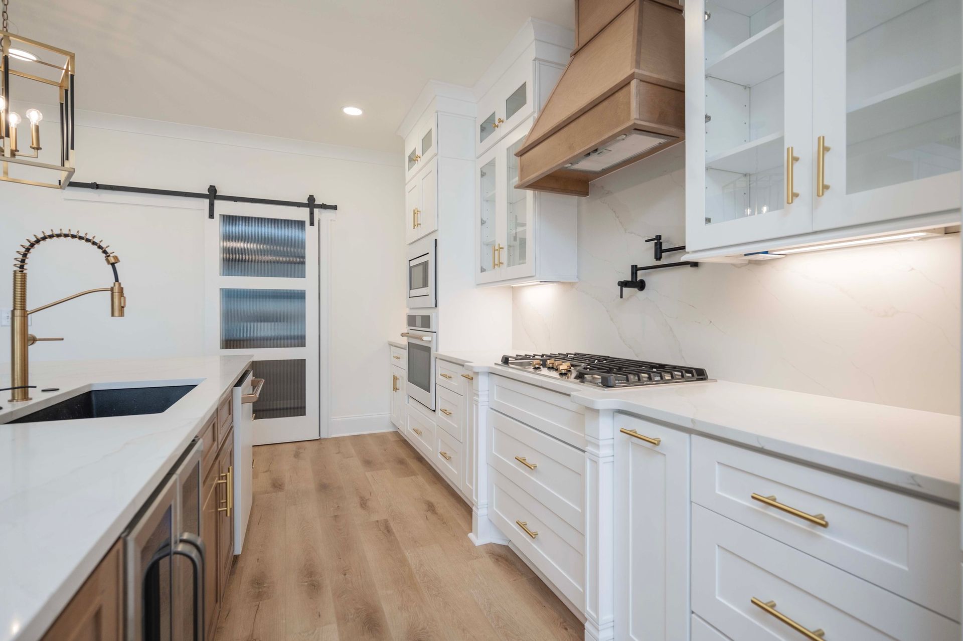 Modern white kitchen with wood accents, including cabinets, range hood, and floor.