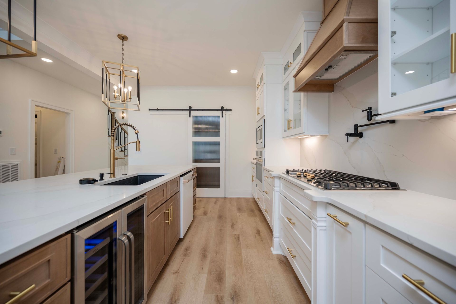 Modern kitchen with white countertops, wooden cabinets, and stainless steel appliances.