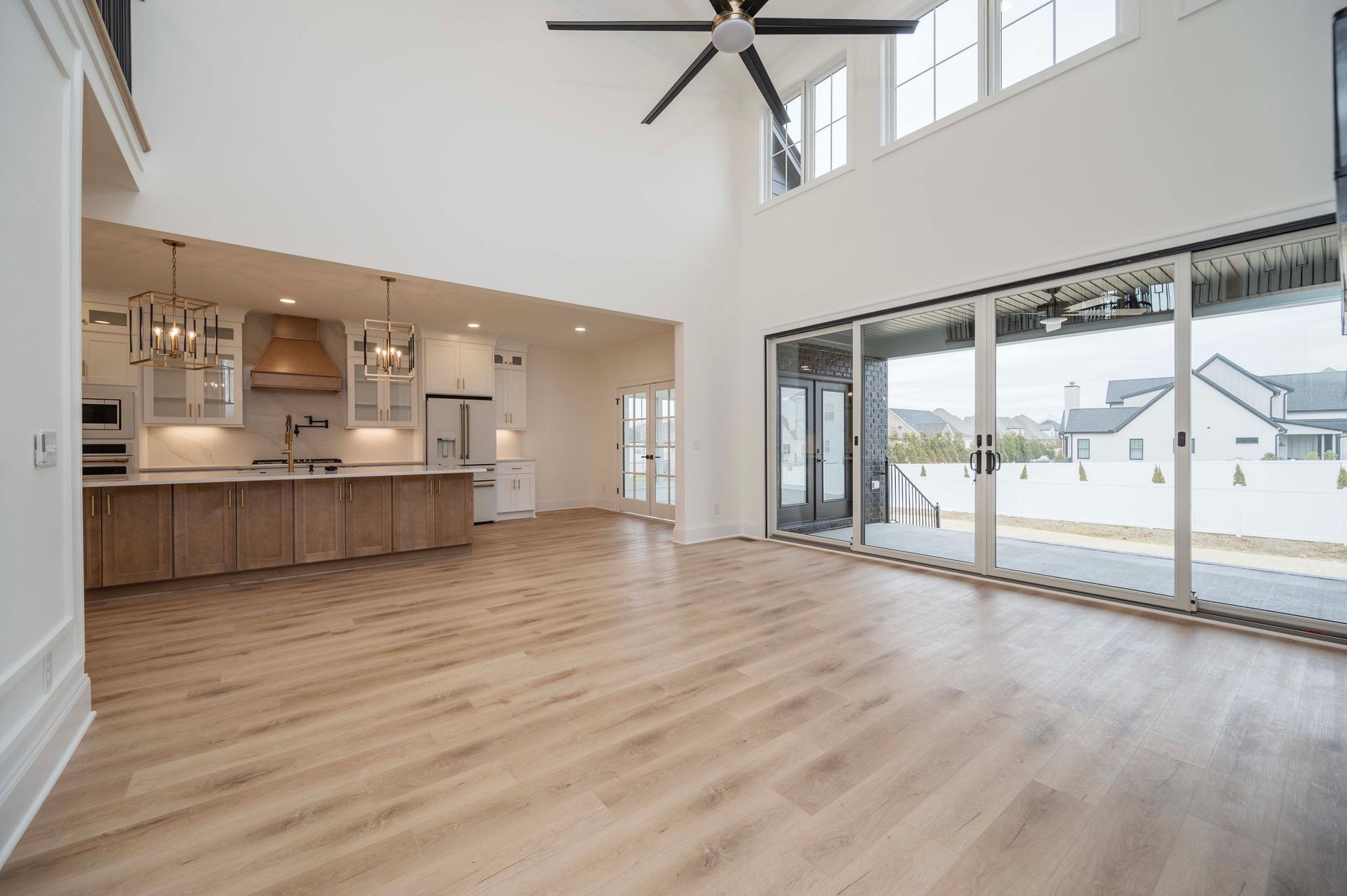 Spacious modern home interior with kitchen, living area, and large glass doors leading to the outdoors.