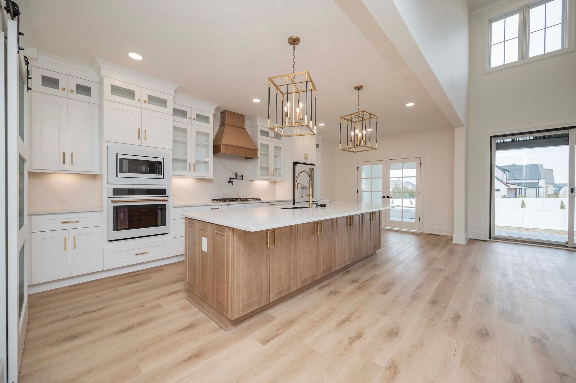 Modern kitchen with white cabinets, wood island, and two gold pendant lights.