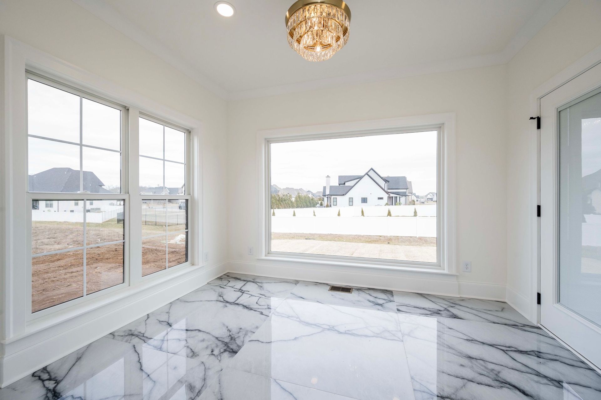 Bright room with marble floors, large windows, and a decorative light fixture.