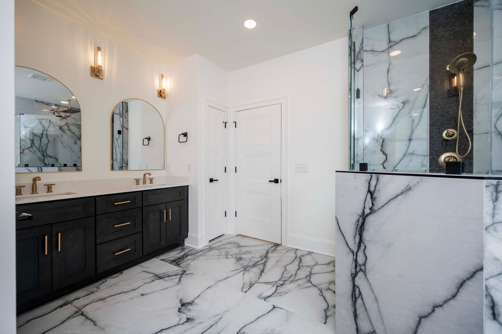 Modern bathroom with black vanity, marble floors, and walk-in shower.