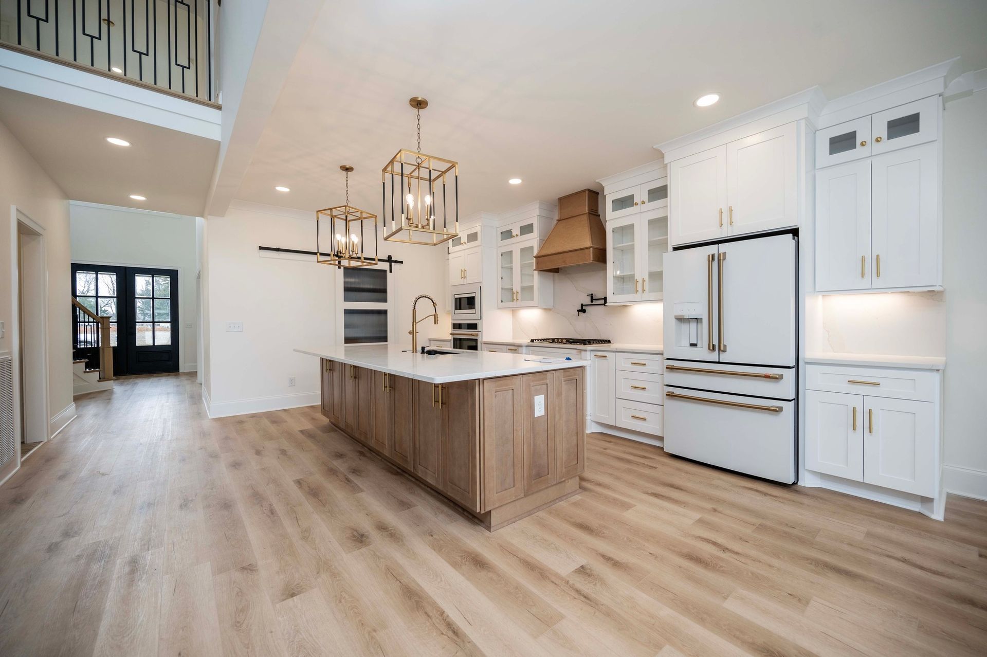 Modern kitchen with island, white cabinets, wood accents, and light wood flooring.