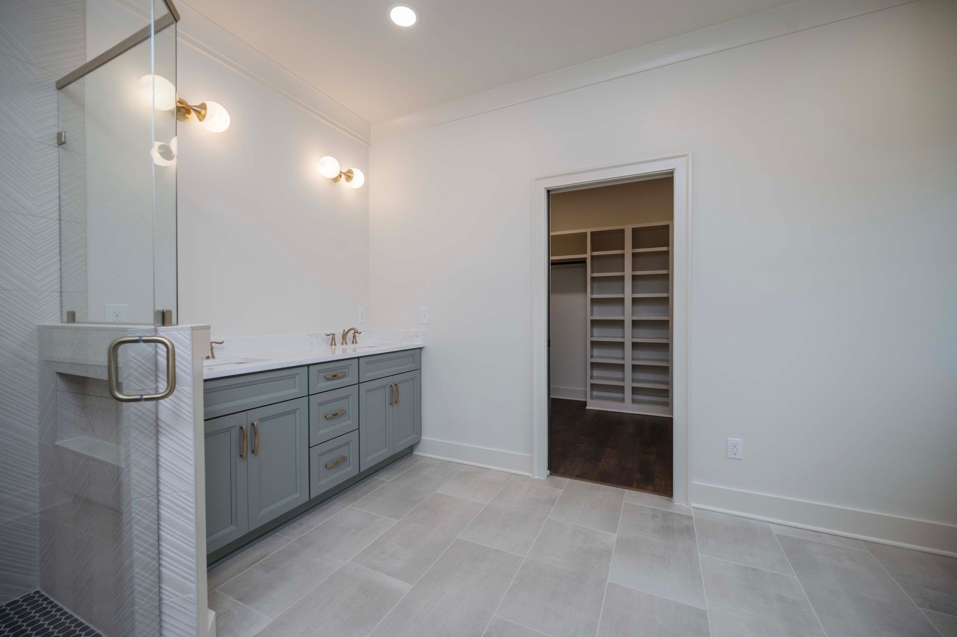 Bathroom with gray cabinets, white countertop, and doorway to a closet.