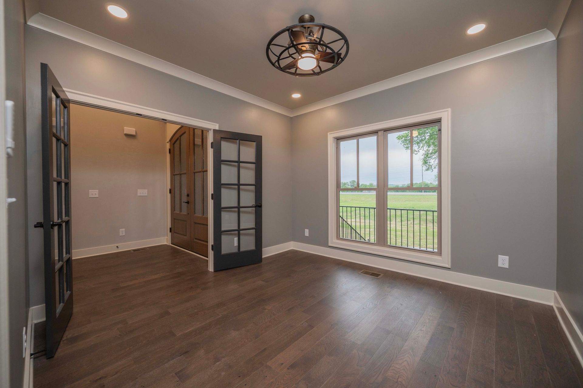 Empty room with dark wood floor, gray walls, and french doors.