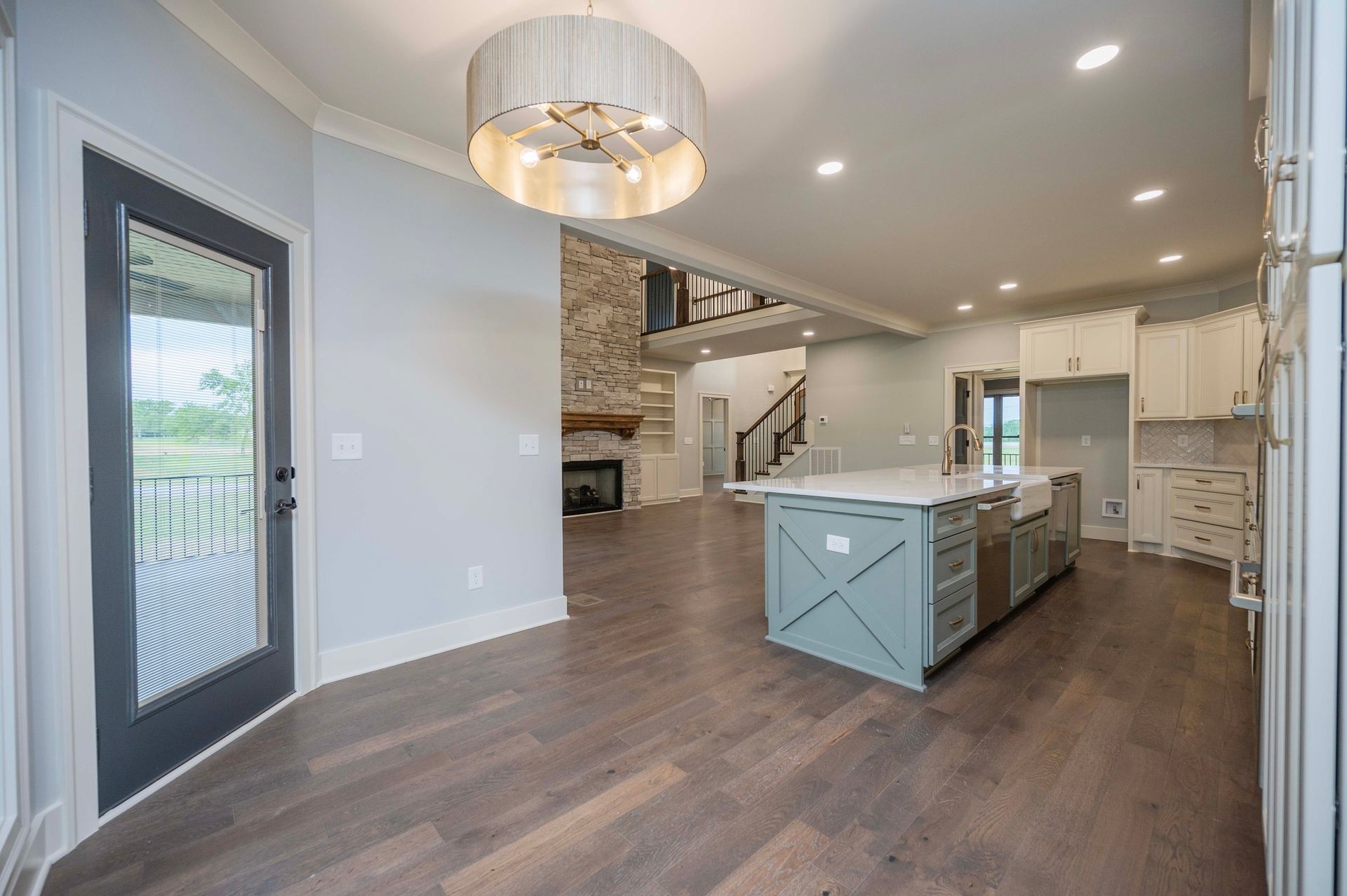 Spacious open-concept kitchen with island, wooden floors, and a stone fireplace.
