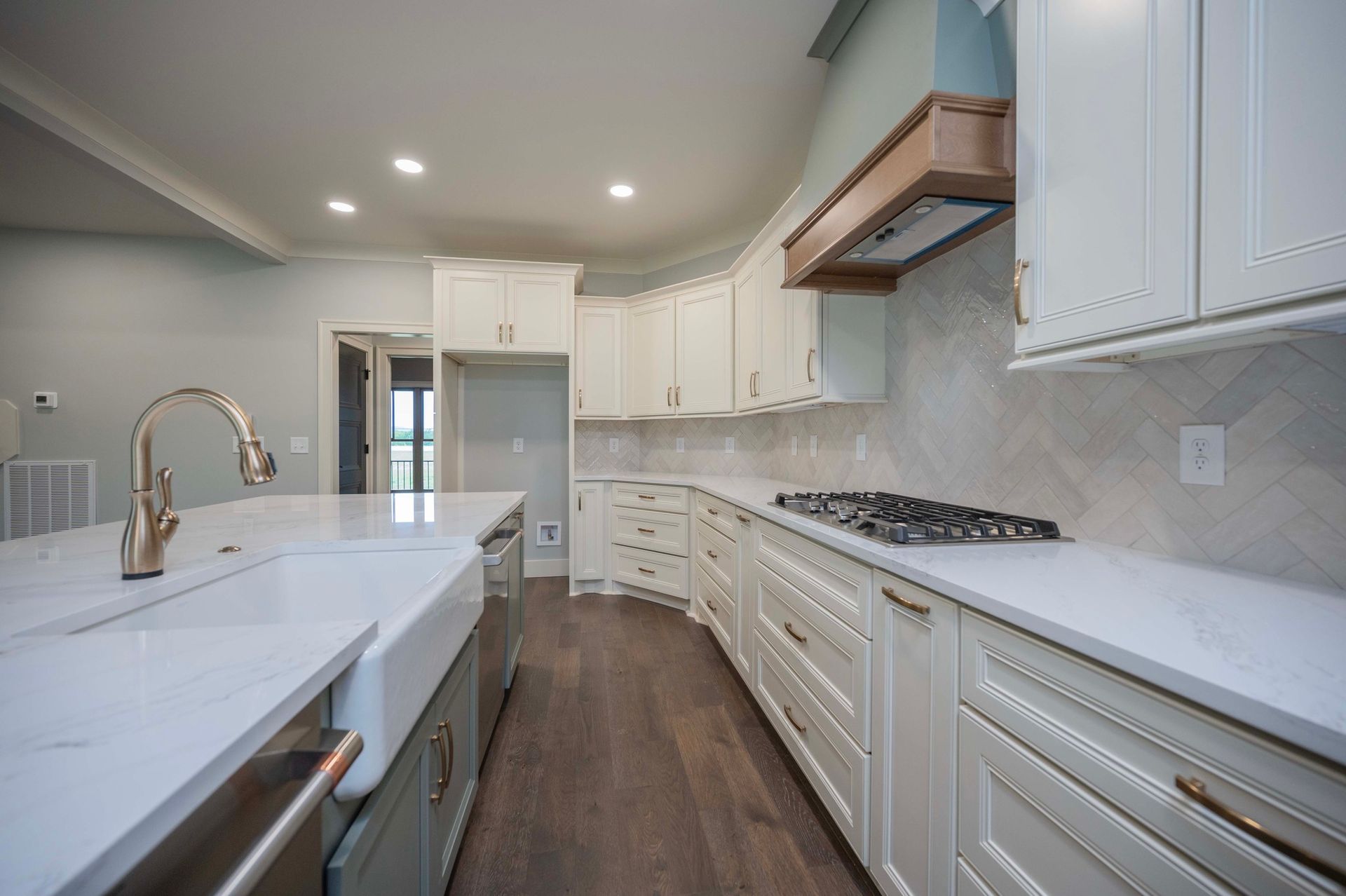 Modern white kitchen with island, quartz countertops, and wooden floors.