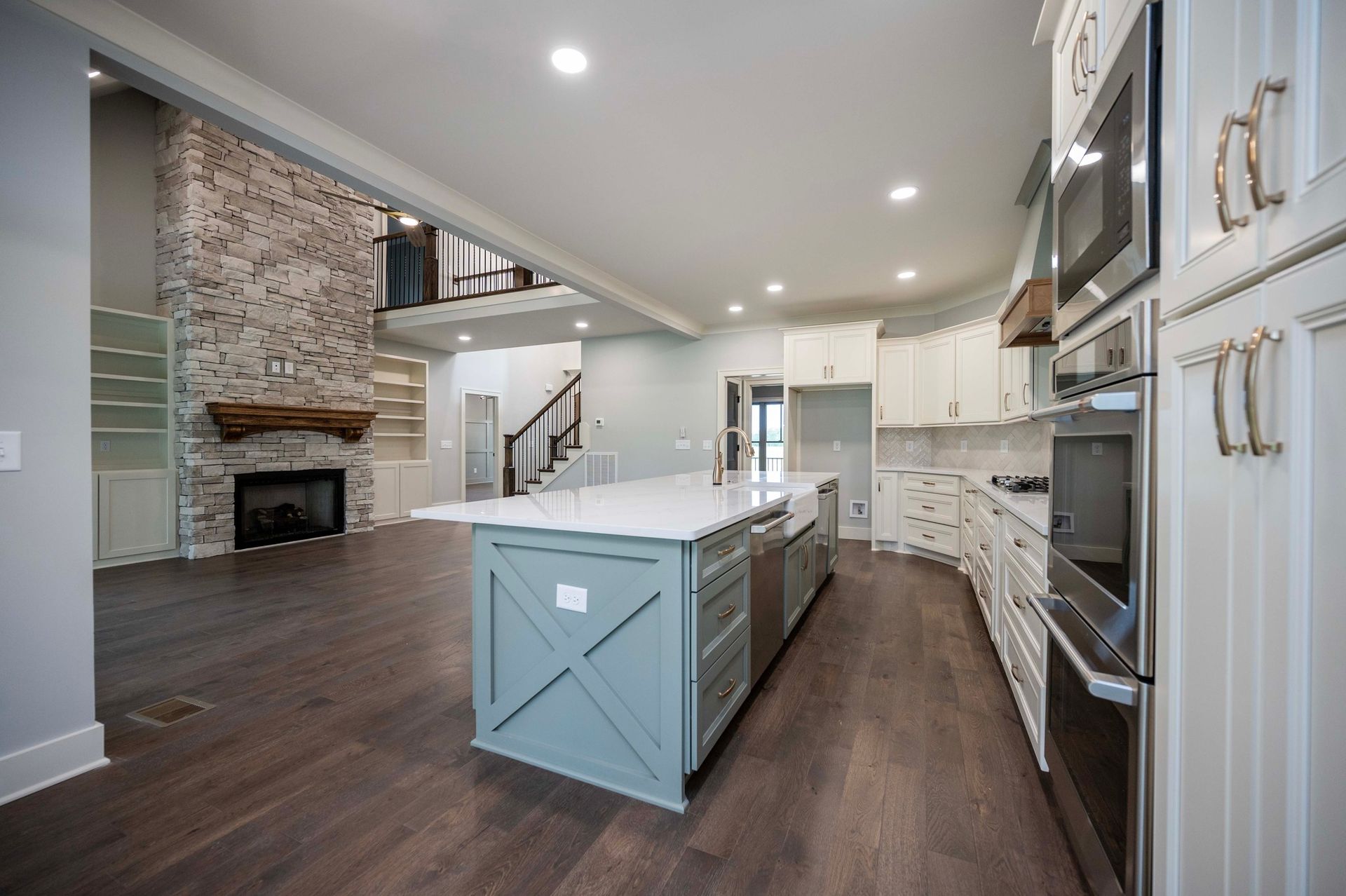 Modern kitchen with blue island, white cabinets, and fireplace.