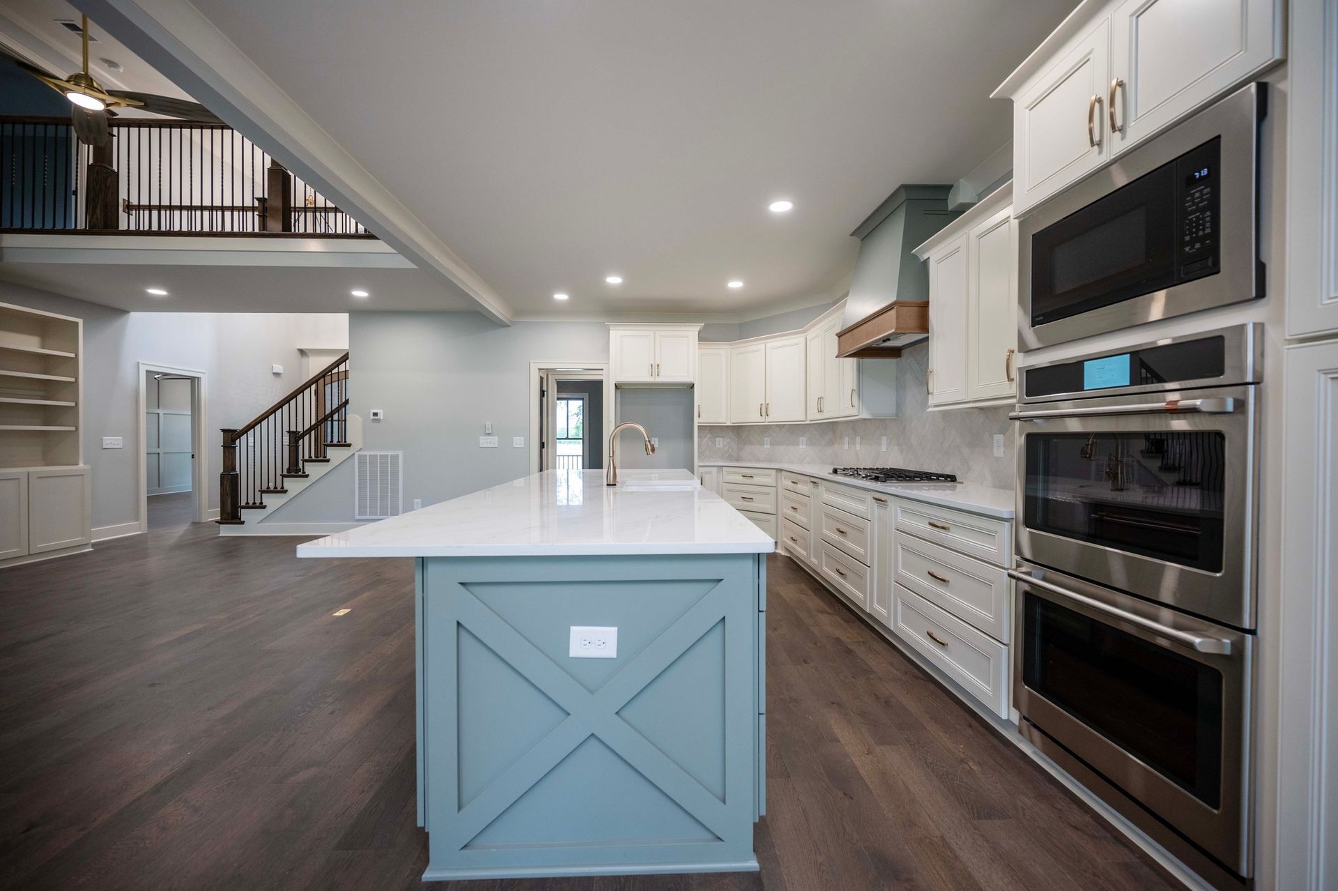 Spacious kitchen with a light blue island, white cabinets, and stainless steel appliances.