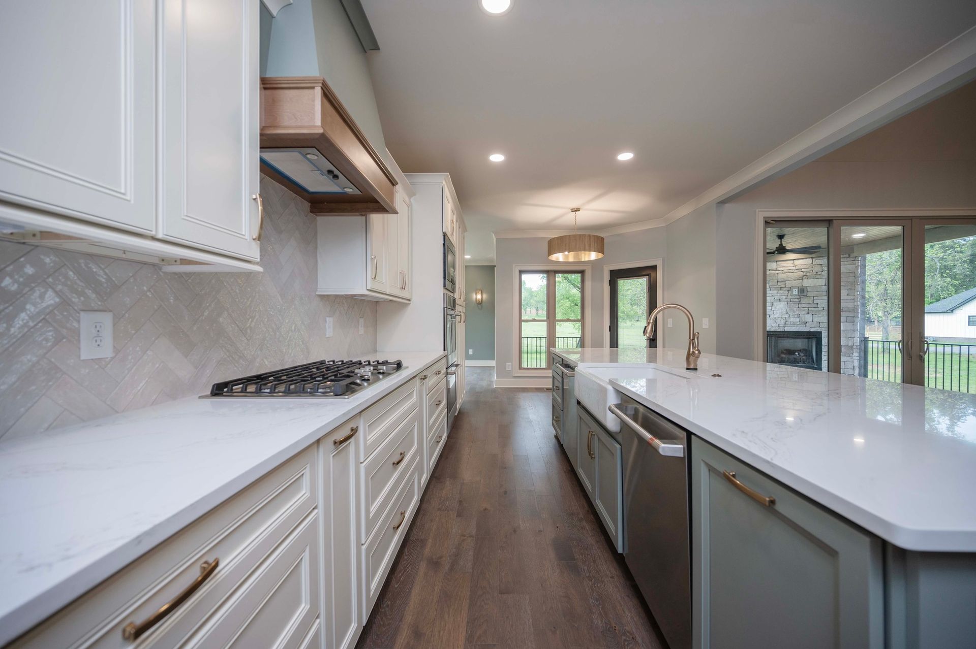 Modern kitchen with white countertops, light cabinets, stainless steel appliances, and hardwood floors.