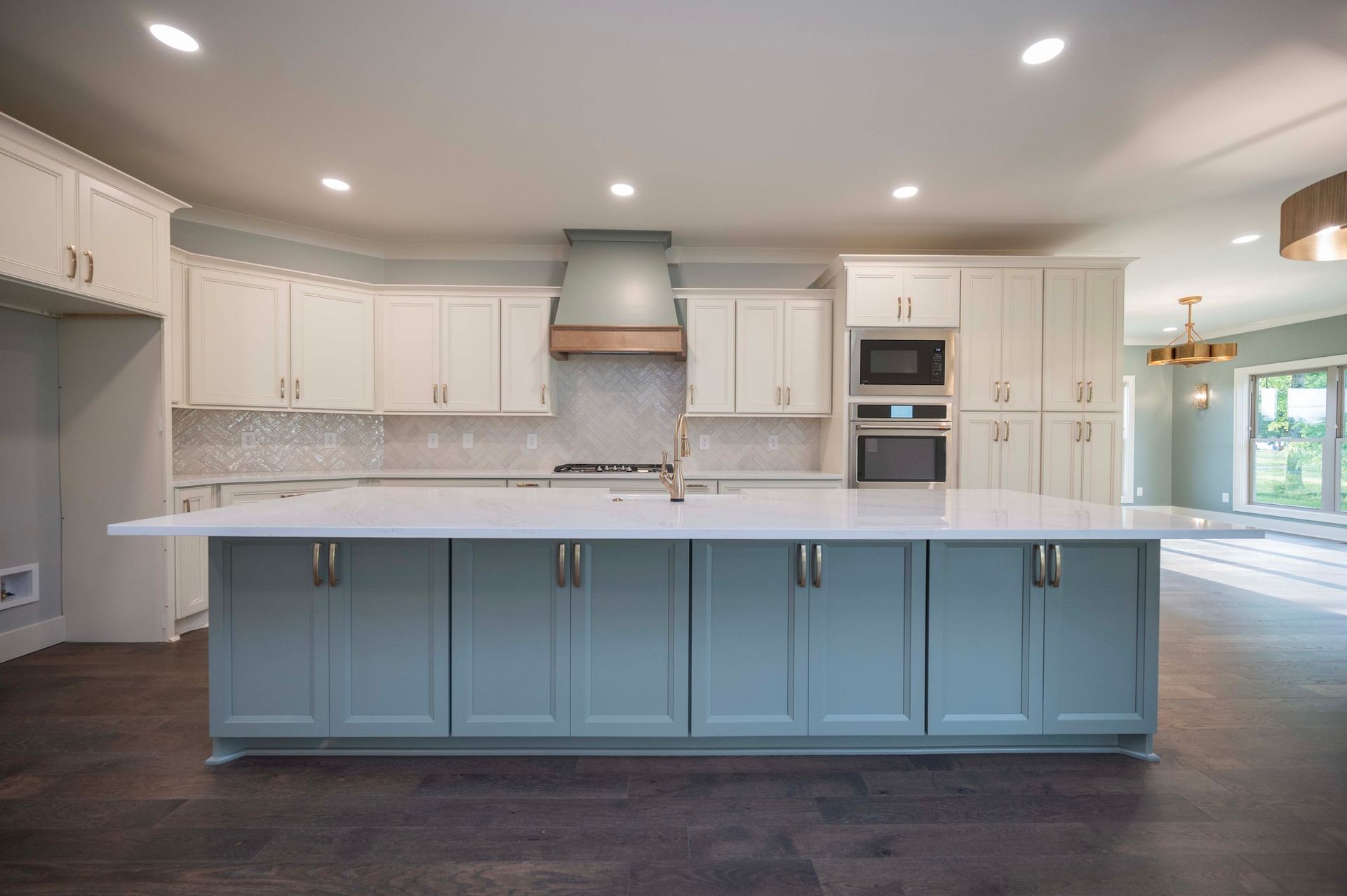 Modern kitchen with blue island, white cabinets, stainless steel appliances, and hardwood floors.