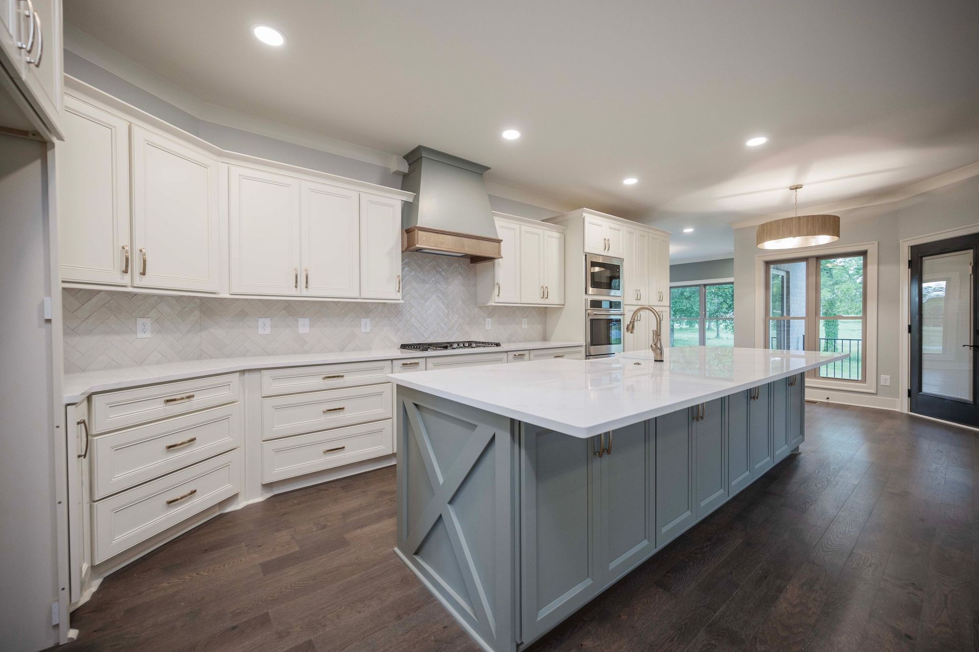 Spacious kitchen with a large island, white cabinets, and wood-look flooring.