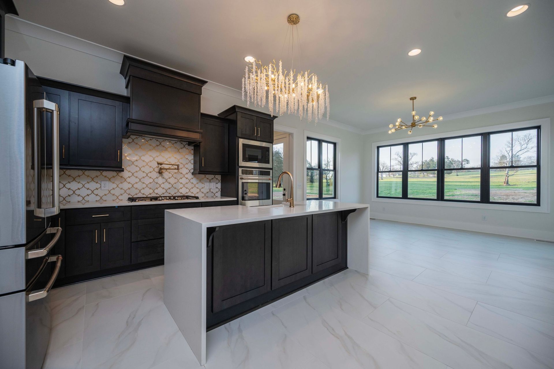 Modern kitchen with dark cabinets, white countertops, and crystal chandelier.