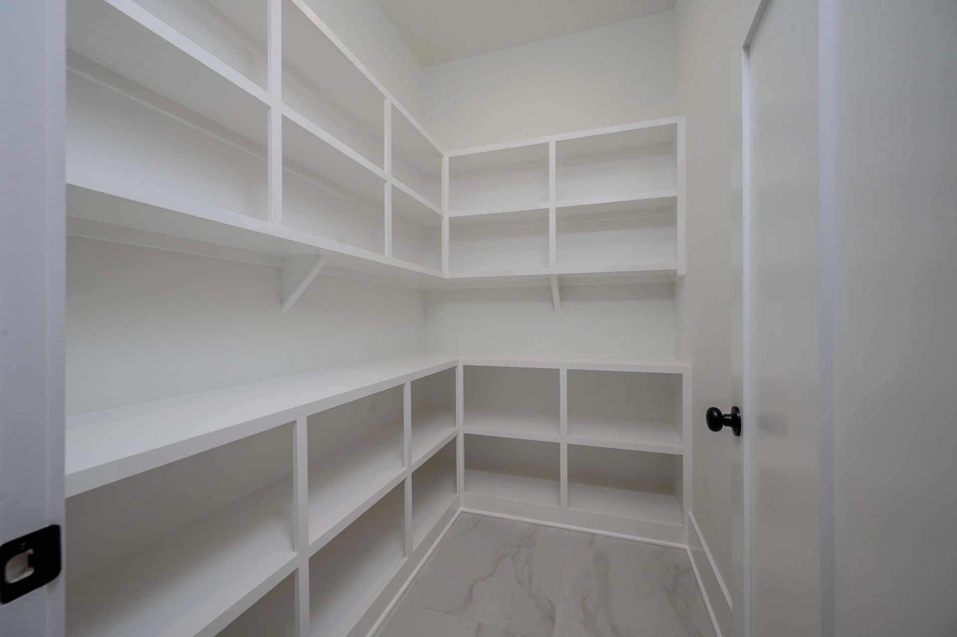 White pantry with built-in shelves. Door is visible on the right.