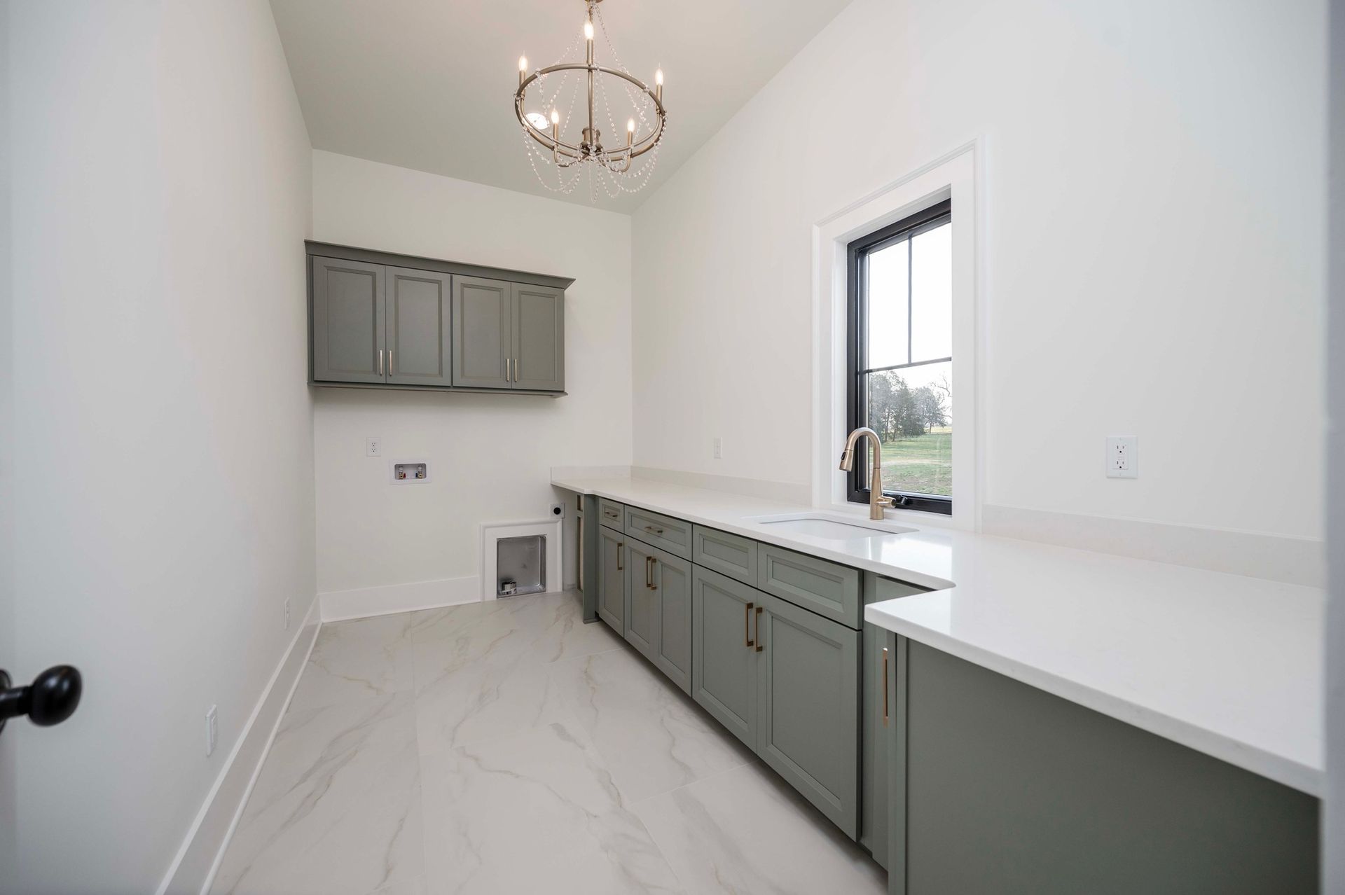 Laundry room with gray cabinets, white countertops, a window, and a chandelier.