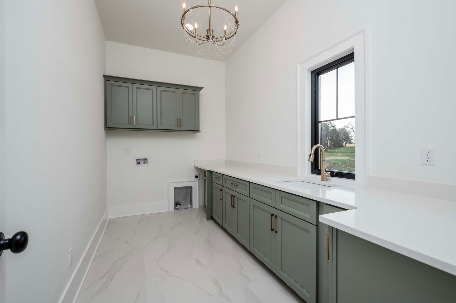 Laundry room with gray cabinets, white countertops, and a window.