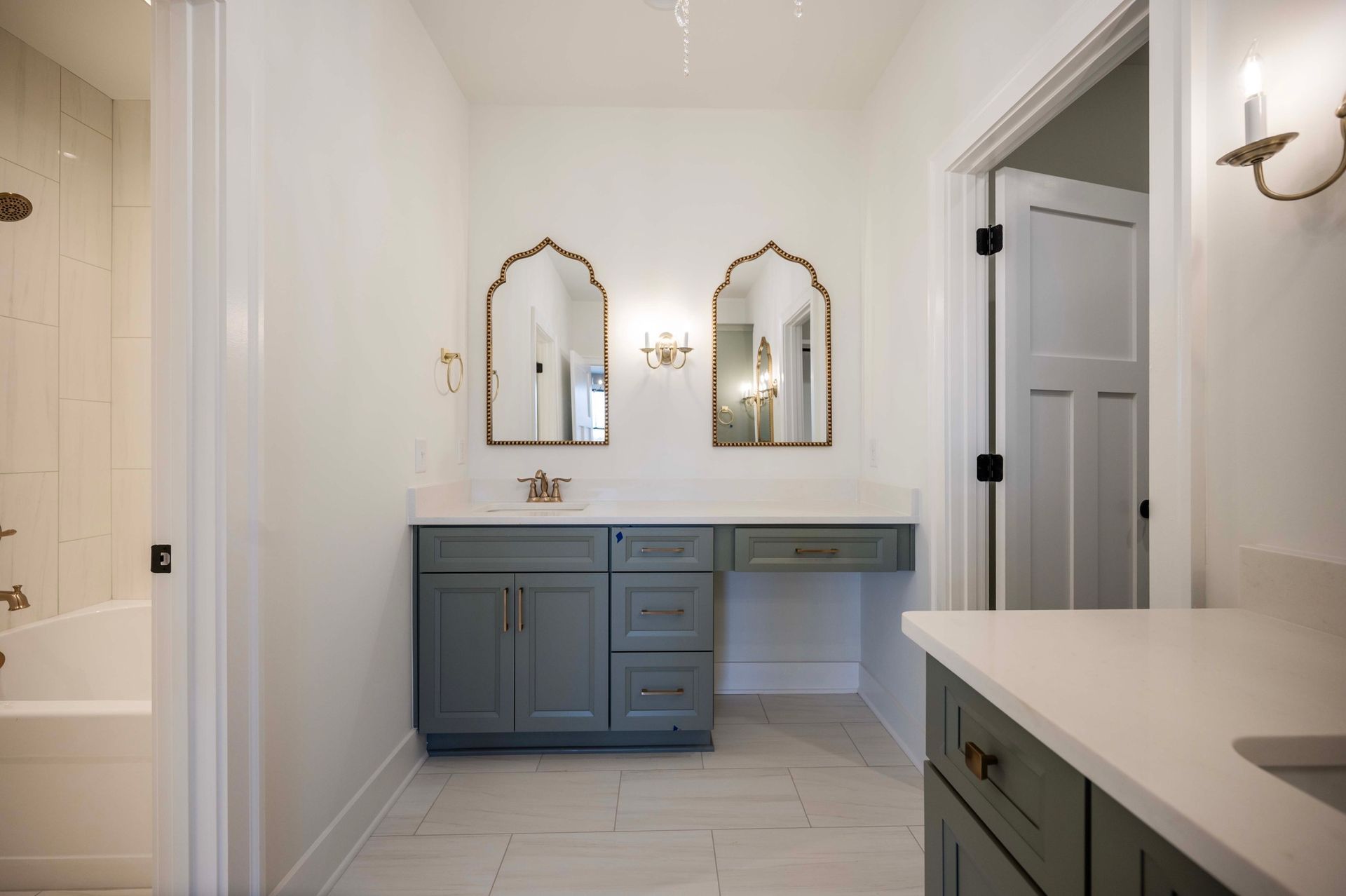 Bathroom with blue vanity, gold mirrors, white walls, and a partially open door.