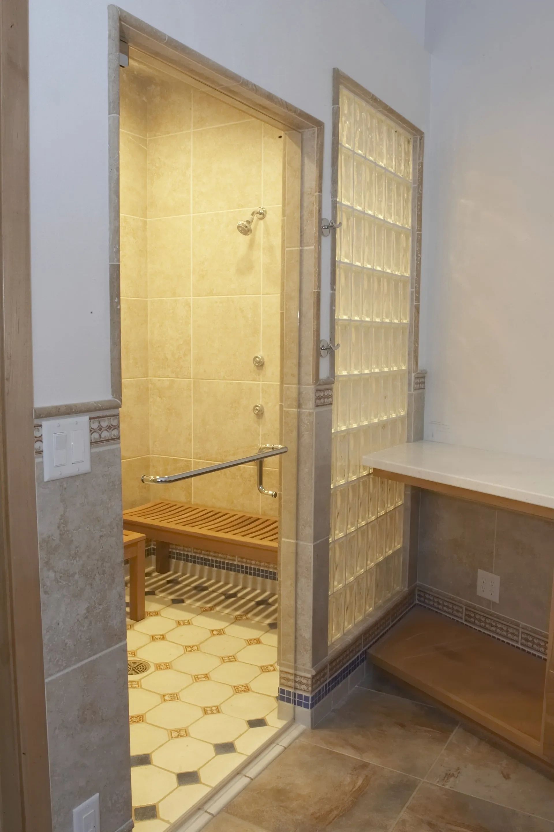 Accessible restroom stall with open door, grab bars, and tiled interior near a sink counter.