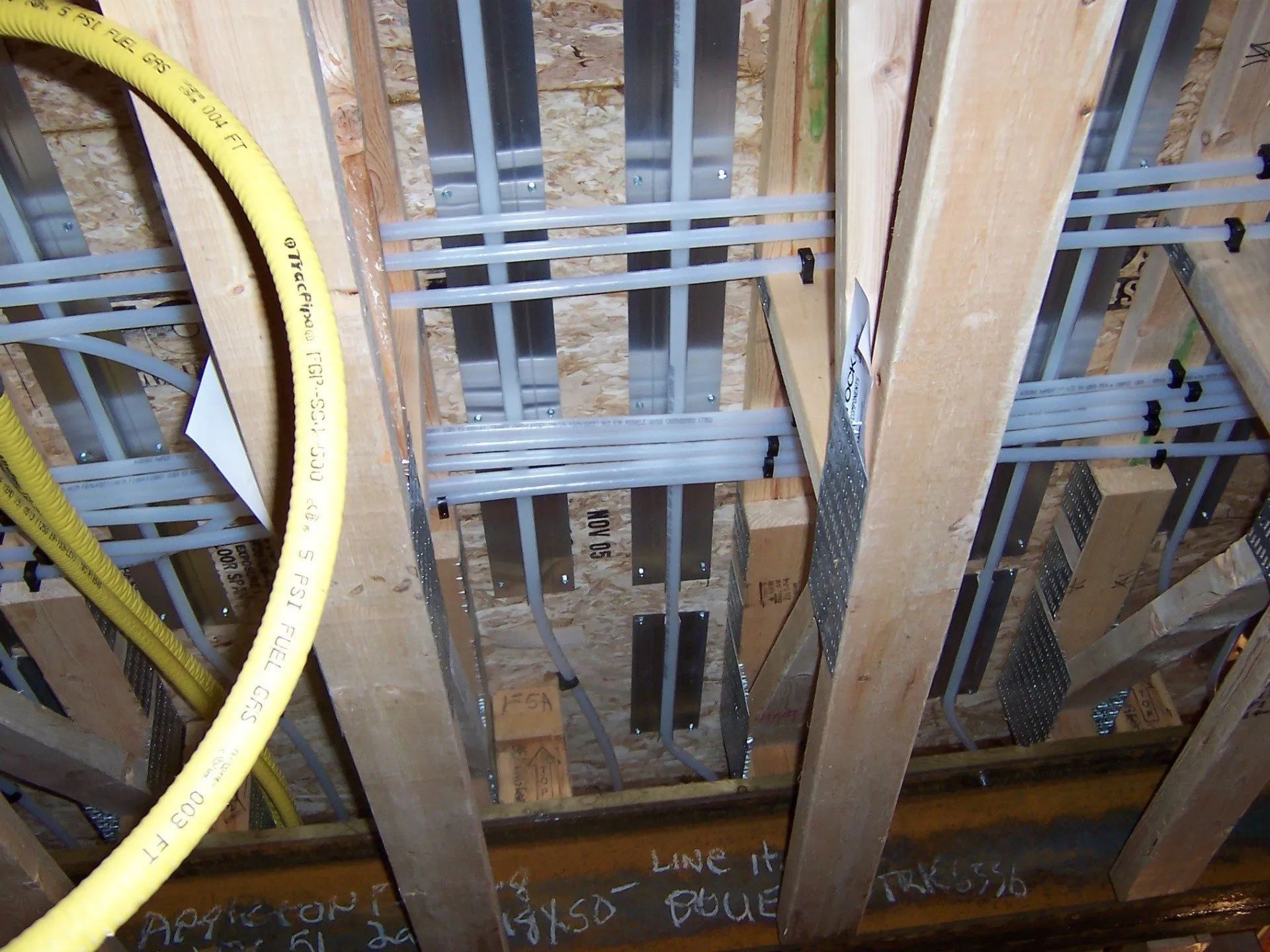 Exposed ceiling framing with wooden beams, metal pipes, and a yellow cable loop on the left