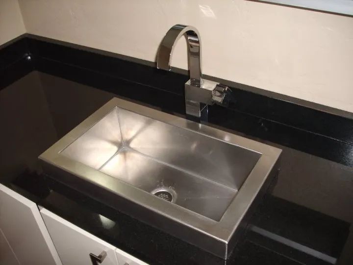 Modern black countertop with a stainless steel sink and chrome faucet in a kitchen.