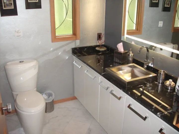 Small bathroom with toilet, black countertop vanity, sink, and mirror