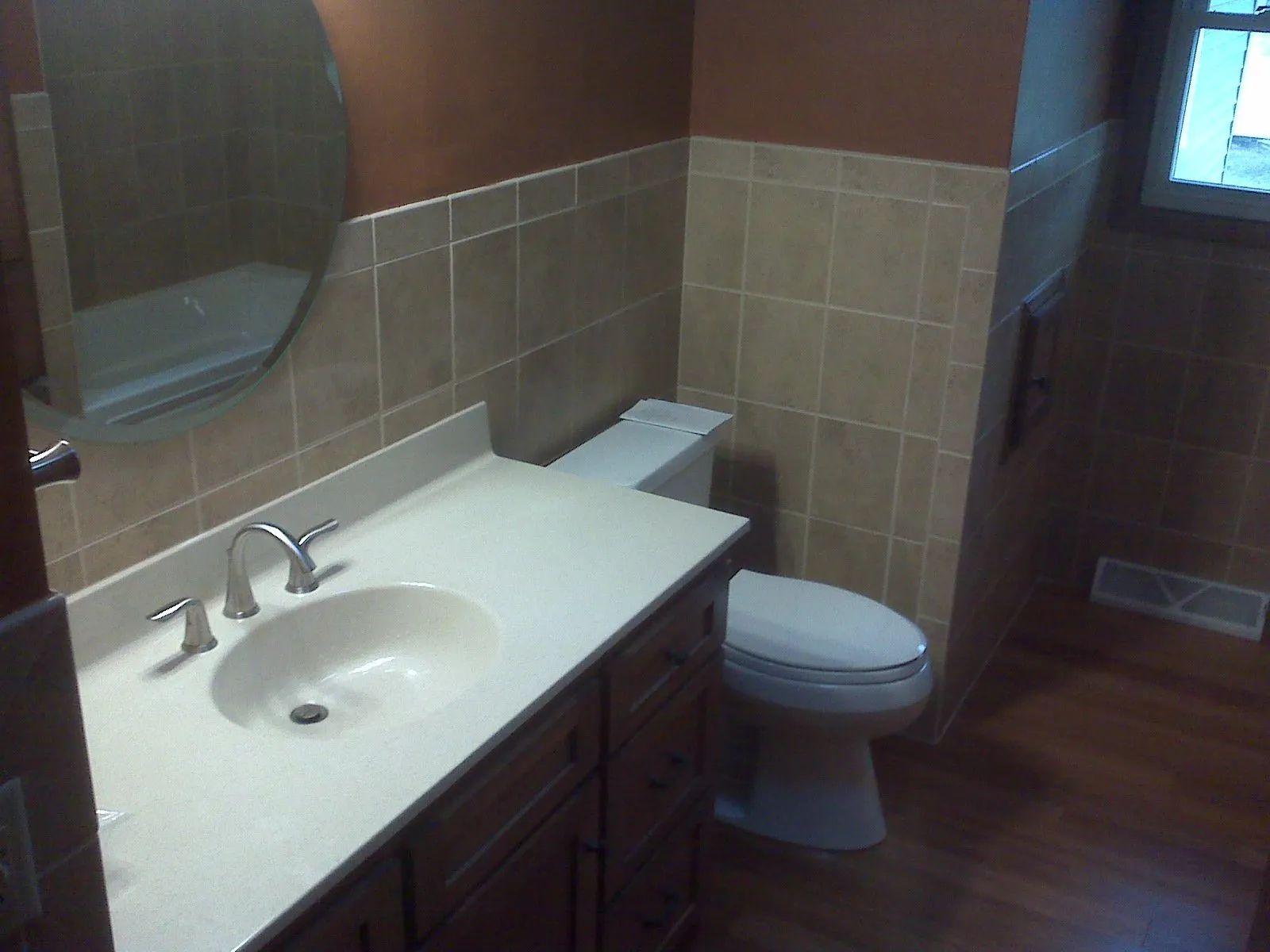 Bathroom with white sink vanity, mirror, toilet, and tan tile walls