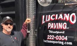A man is standing in front of a truck that says  Luciano Paving