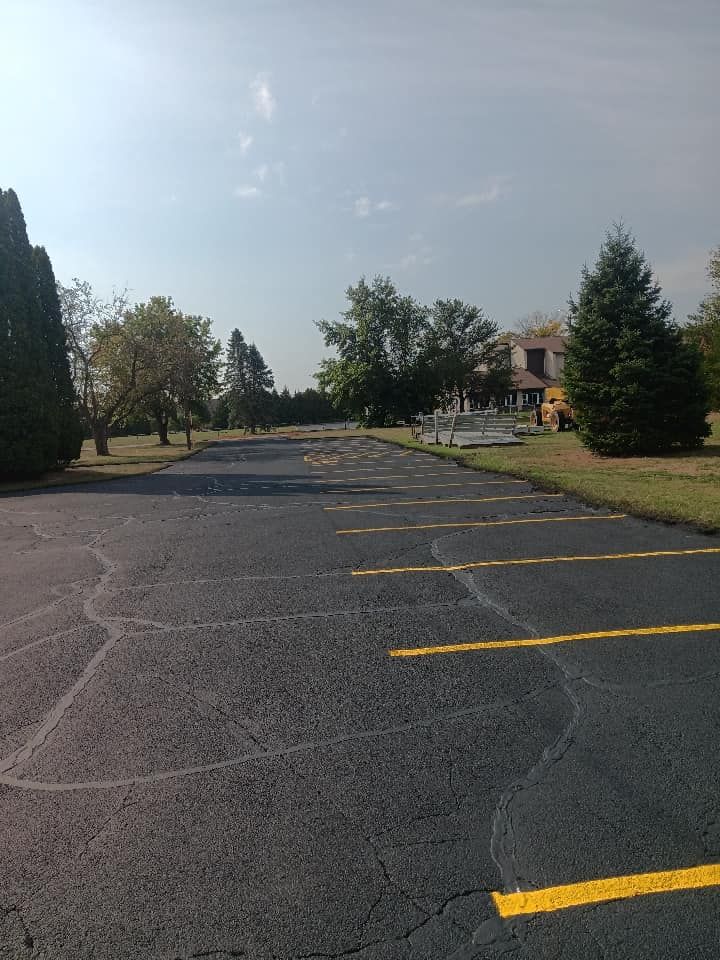 A parking lot with yellow lines and a house in the background.