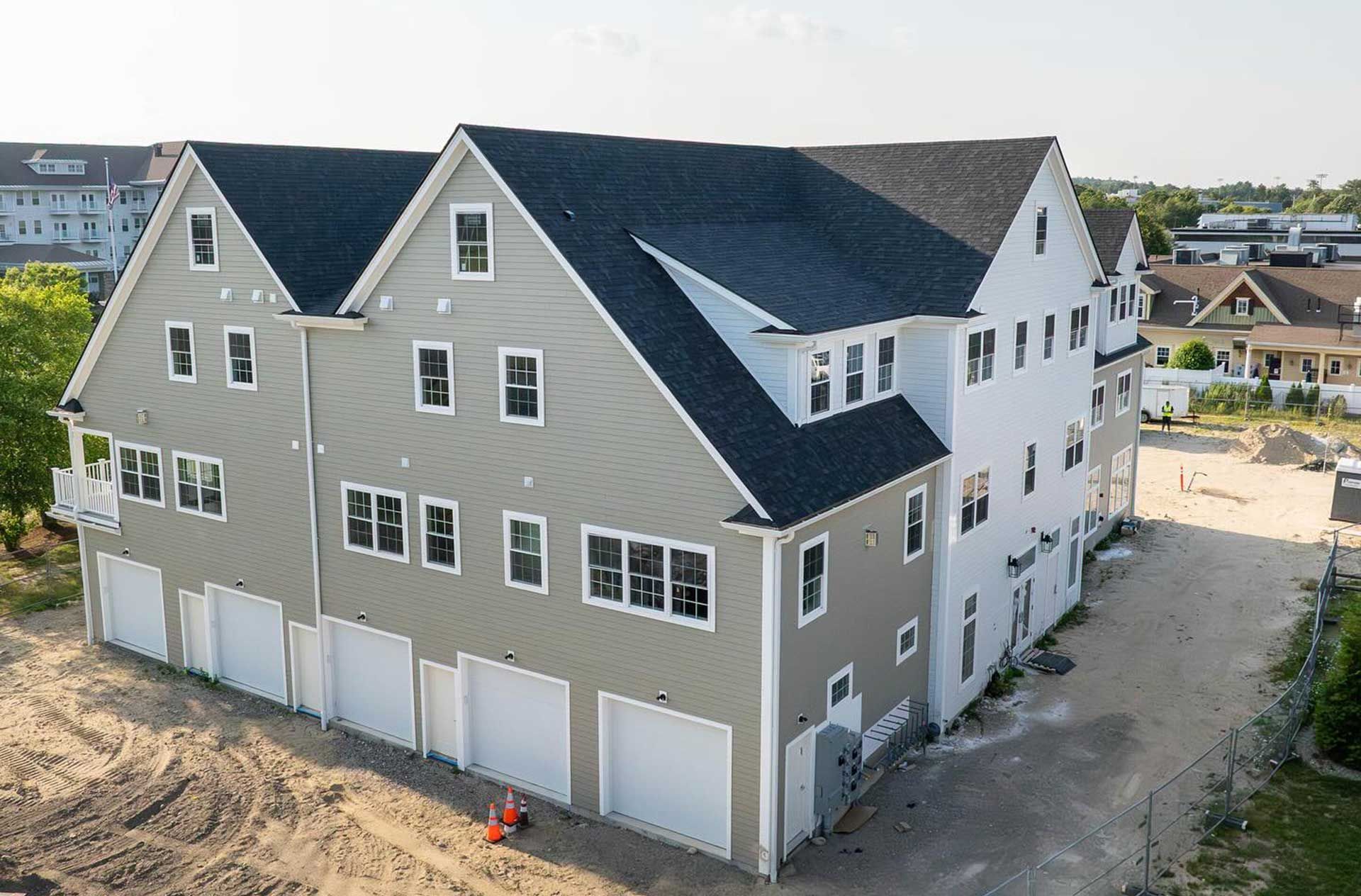 Multi-story residential building with attached garages; gray and white siding, black roof.