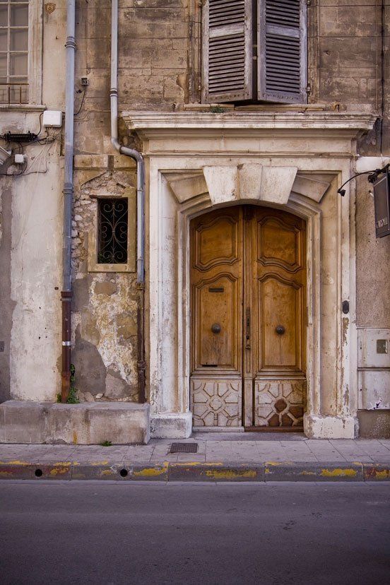 Ornate wooden double doors in aged stone building facade.