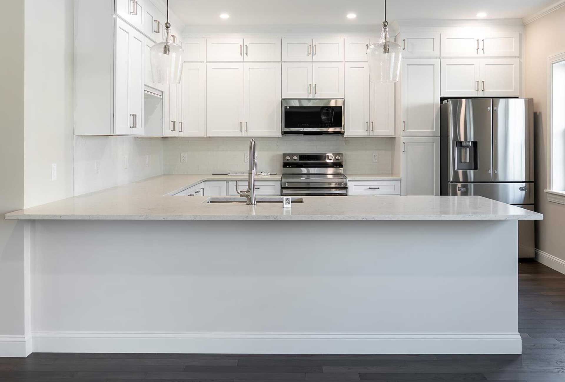 White kitchen with overhead cabinets, stainless steel appliances, and island with countertop.