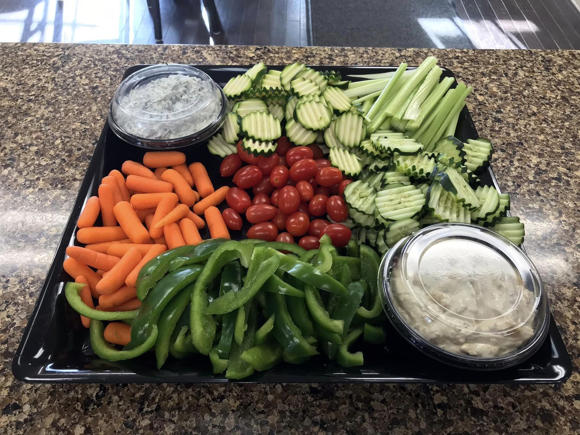 A tray of vegetables and dips on a counter