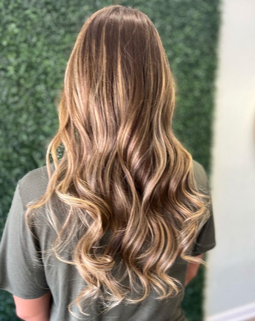 Woman with long, wavy, highlighted blonde and brown hair. She is wearing a green shirt.