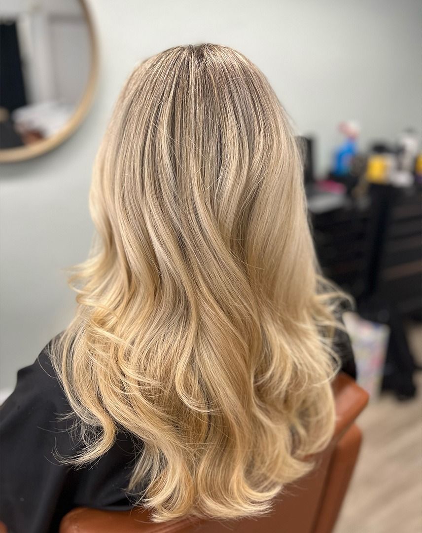 Blonde hair styled with crimped roots and loose waves, client in salon chair.
