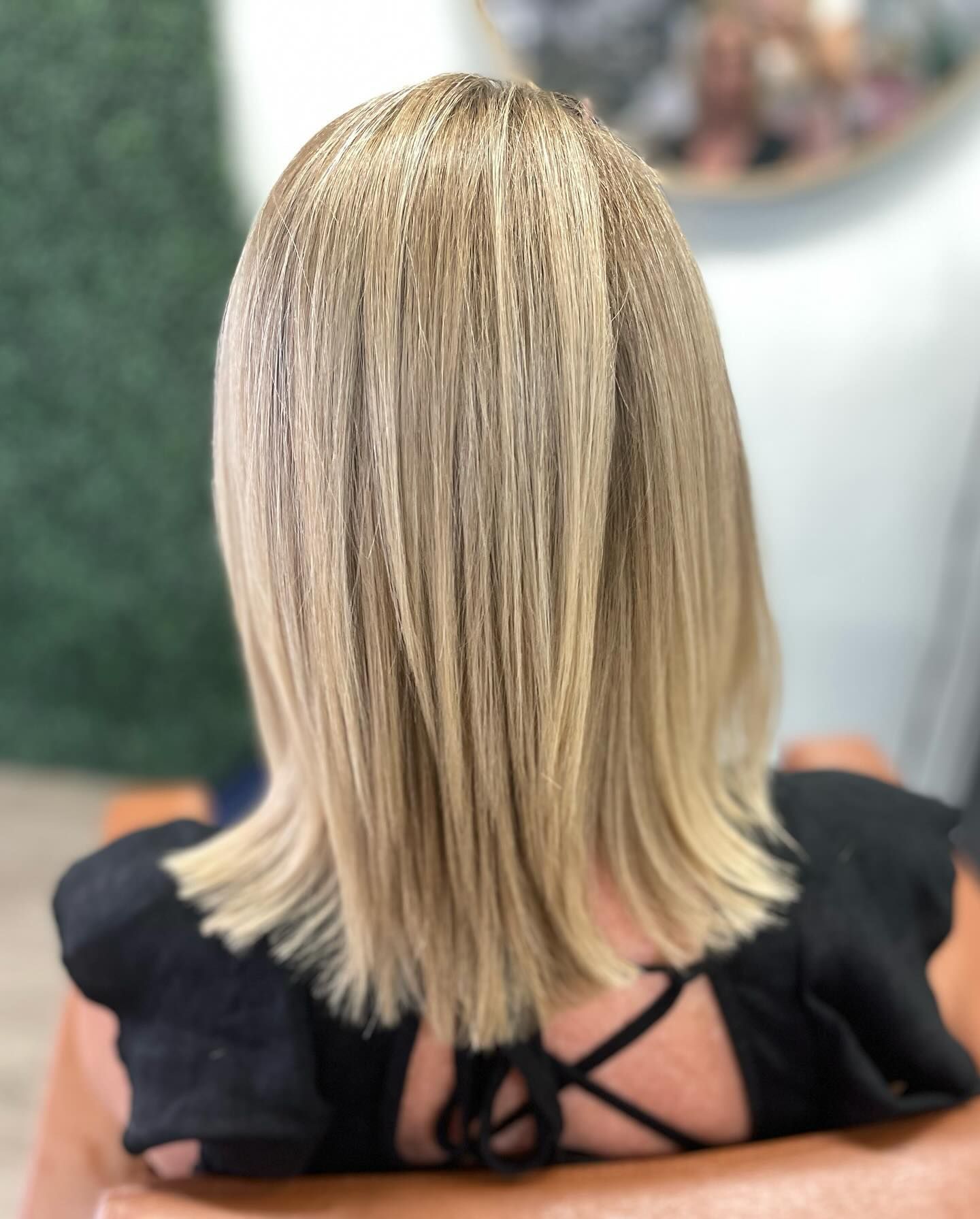 Blonde bob haircut with subtle highlights; black shirt with open back.