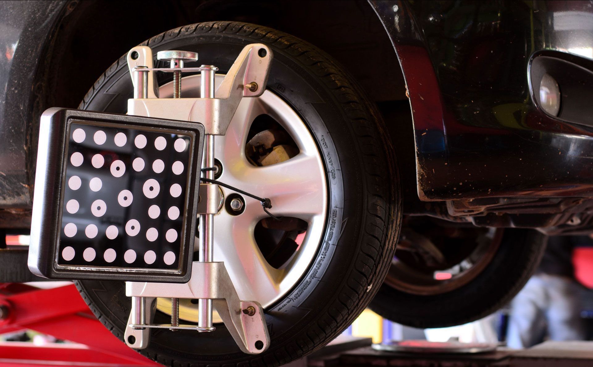 A car is being adjusted on a lift in a garage.