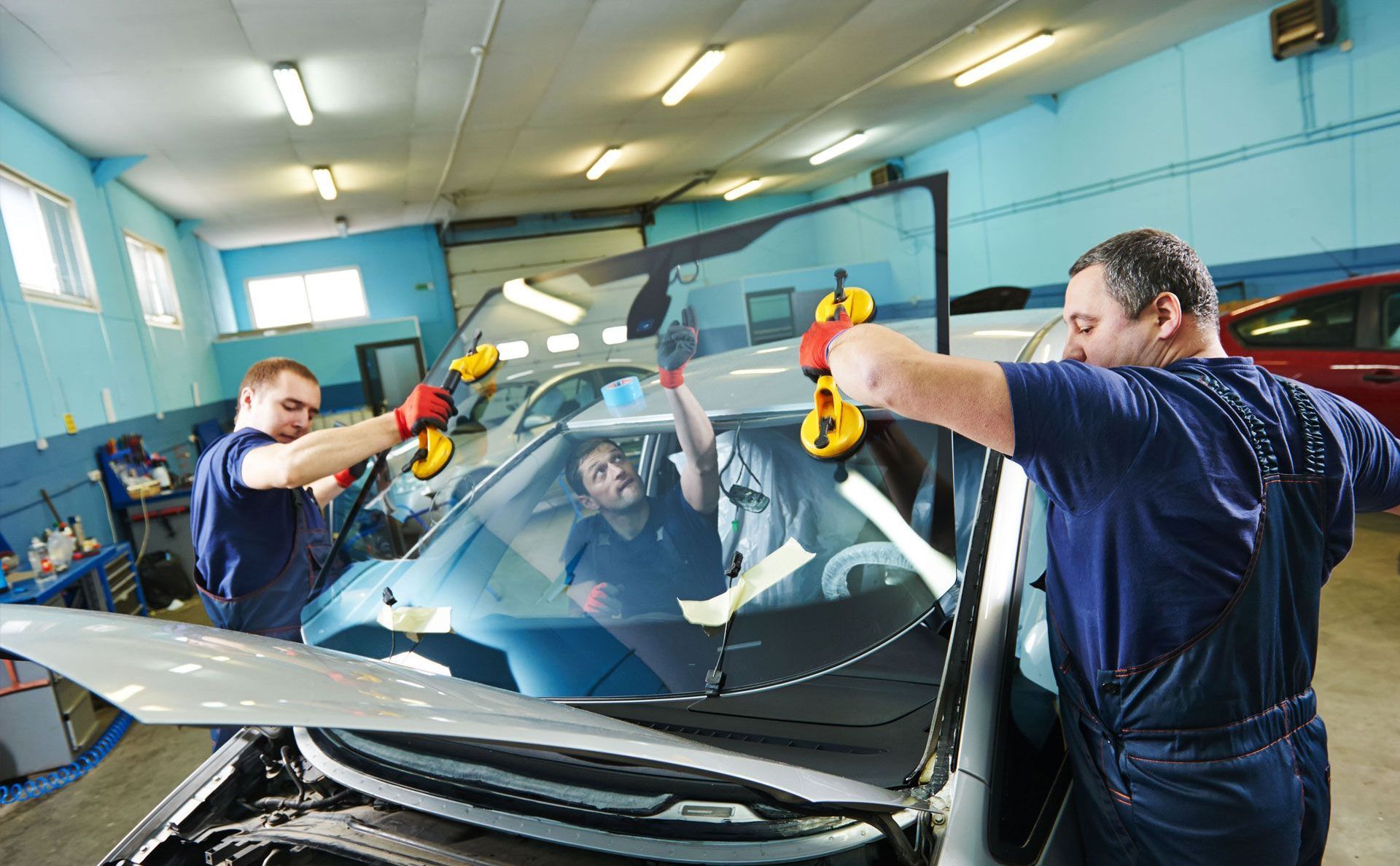 A man is installing a windshield on a car.