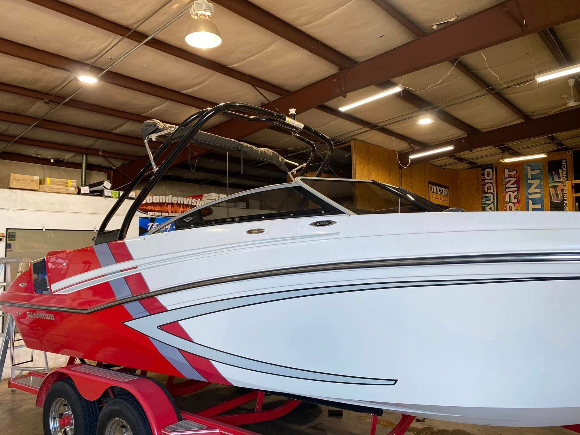 Red and white speedboat on a trailer inside a warehouse garage
