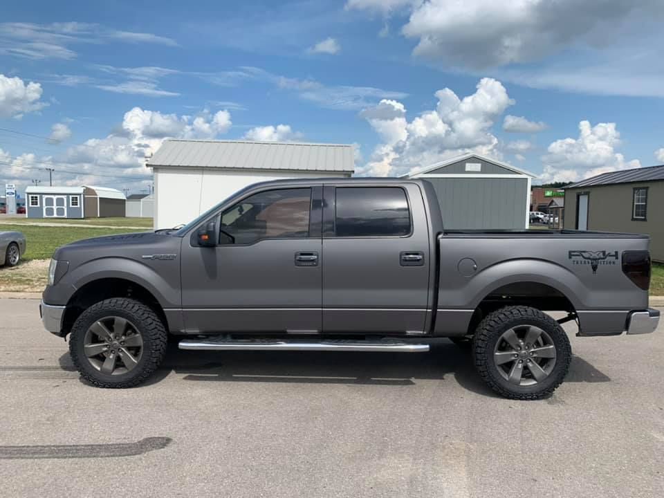 Gray pickup truck parked in front of a house under a cloudy sky