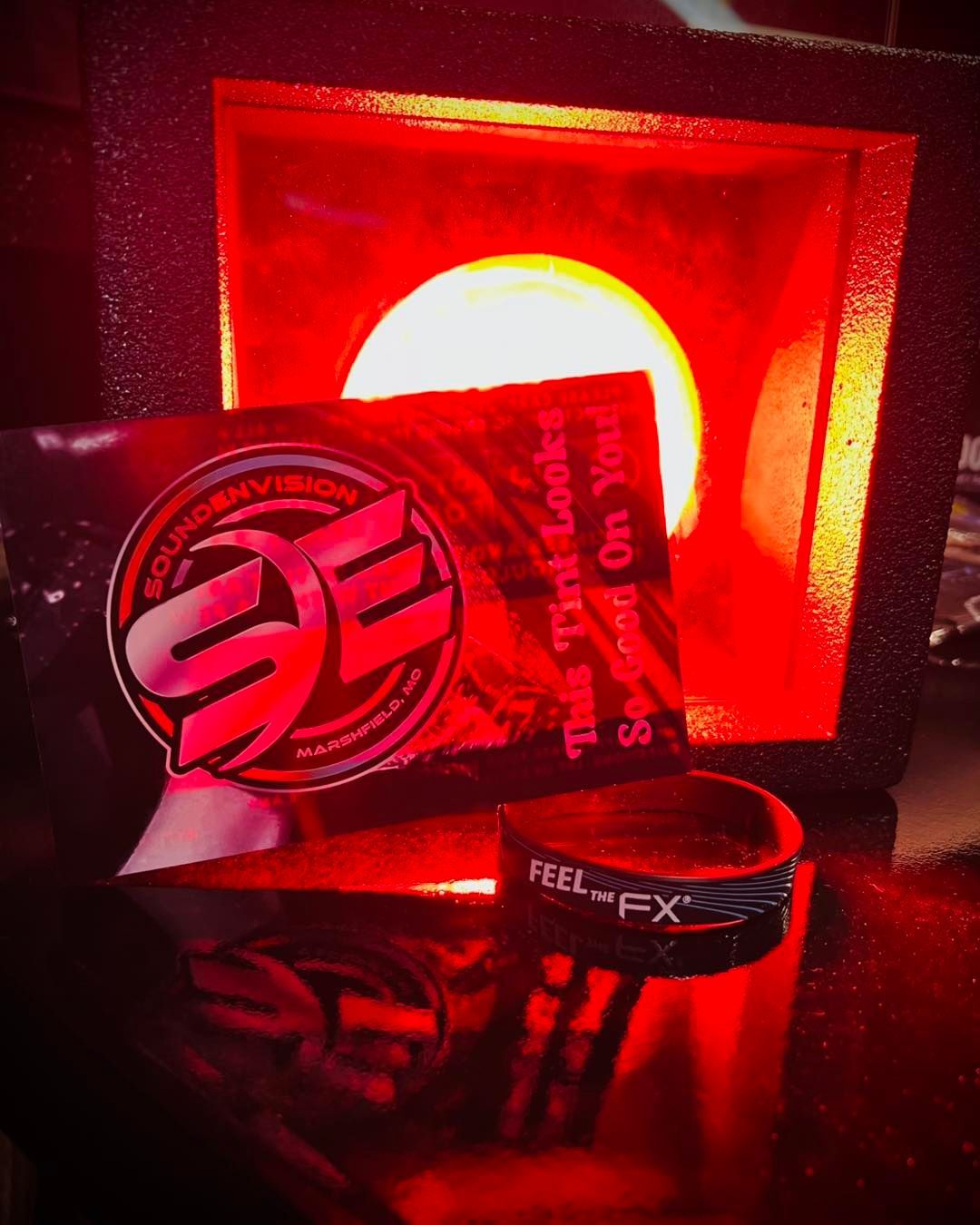 Red-lit display of a Freelex card, bracelet, and logo plaque on a glossy surface