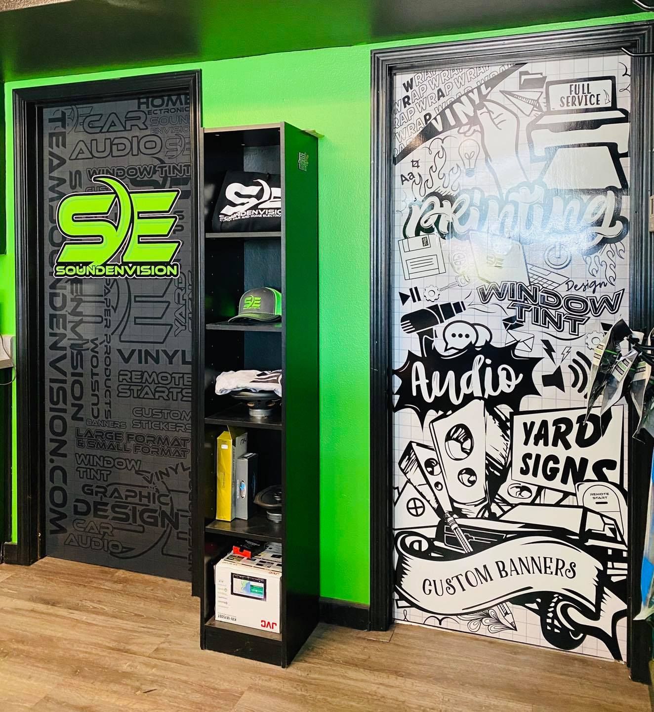 Black-and-neon green signage wall with a display shelf and a graffiti-style door reading “Audio” and “Hard Signs”