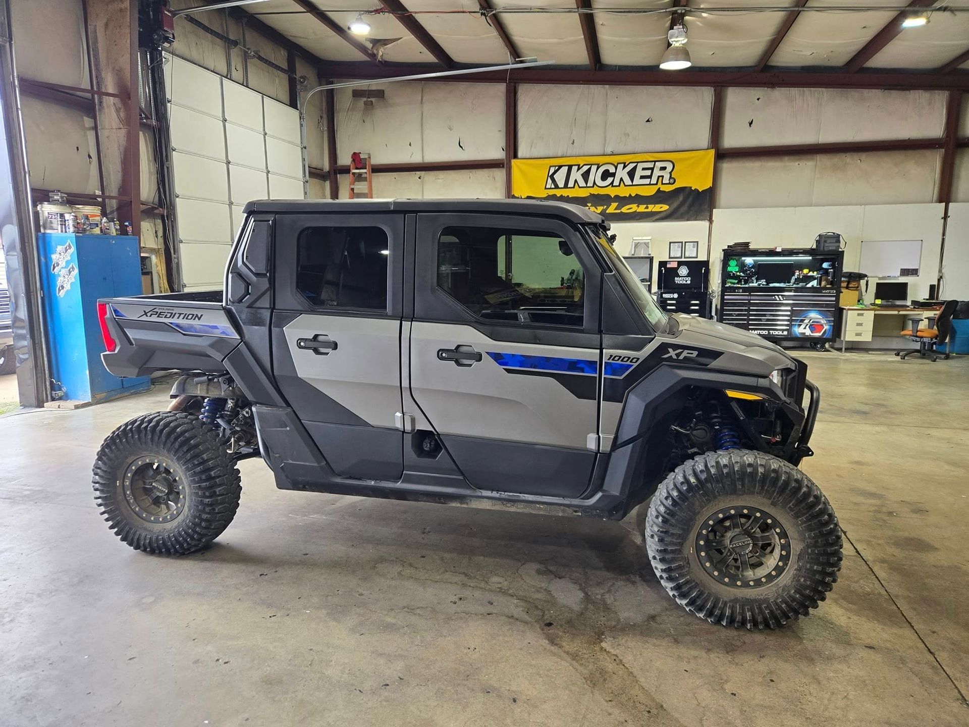 Lifted gray off-road SUV in a garage, with oversized tires and black accents.
