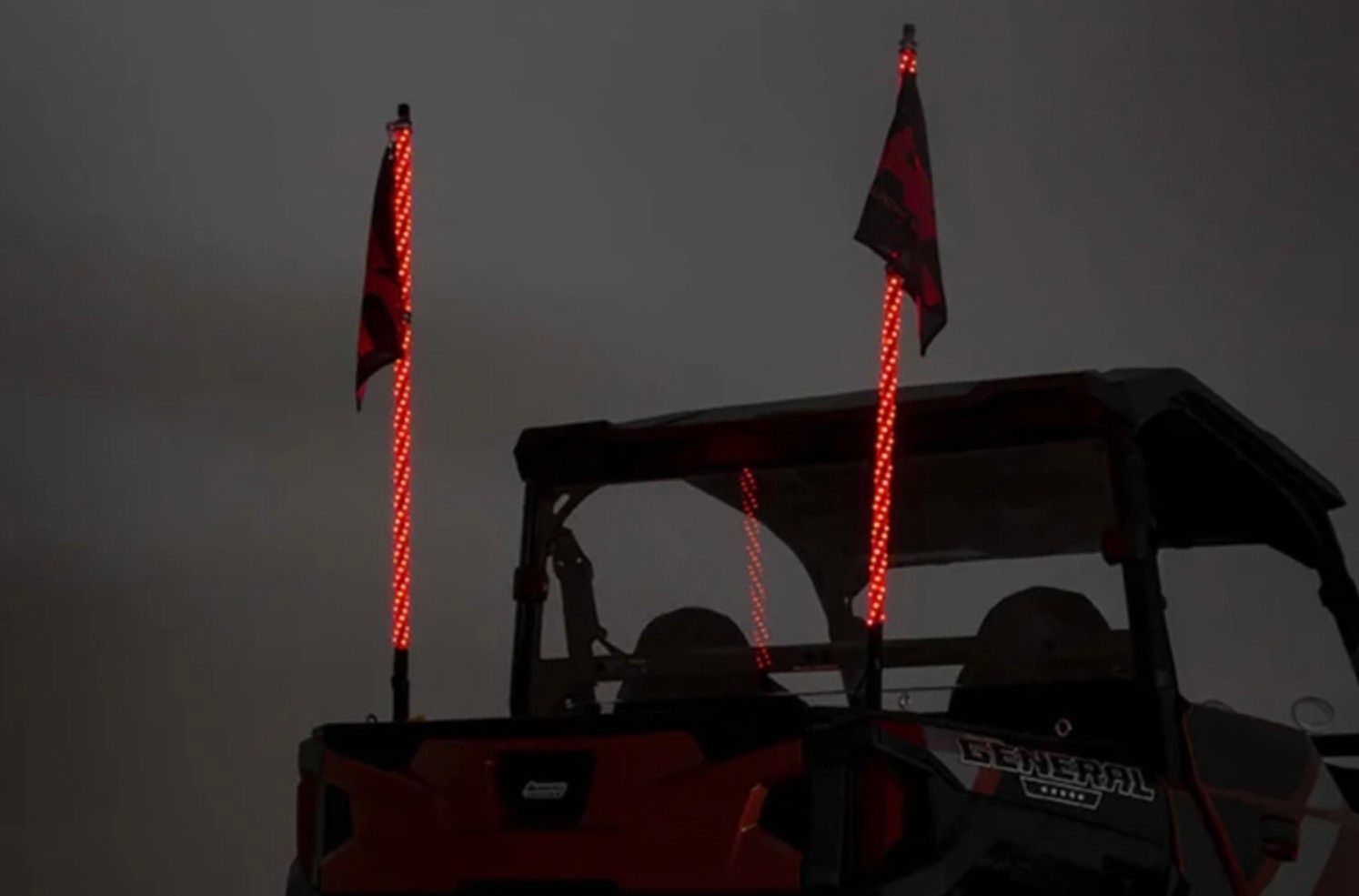 Red off-road vehicle with glowing red light poles at dusk or night