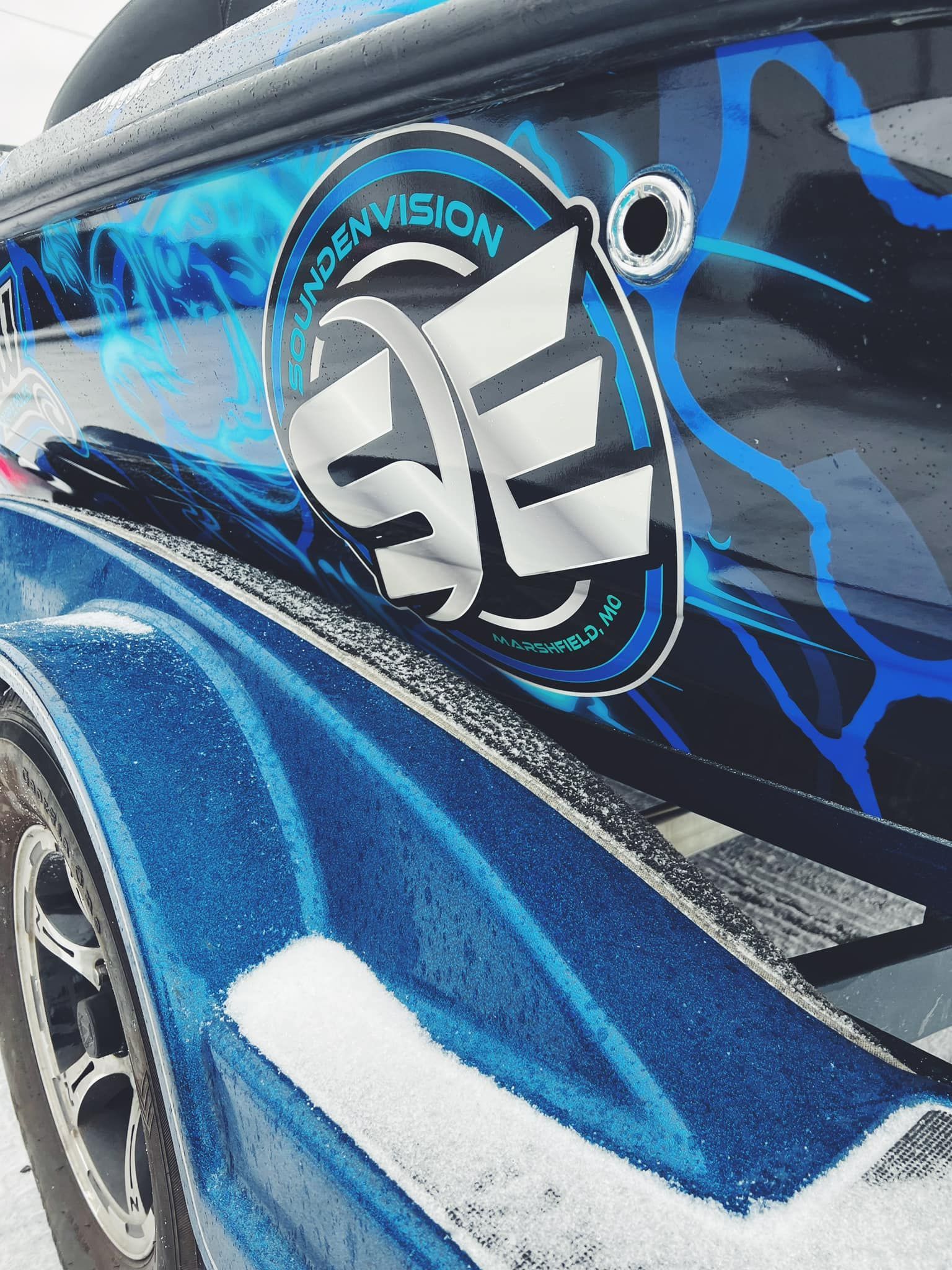 Close-up of a blue customized car door with a large silver emblem and black lightning-style graphics