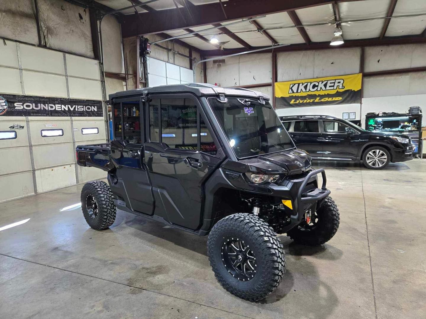 Black off-road UTV with lifted suspension and large tires in a garage shop setting